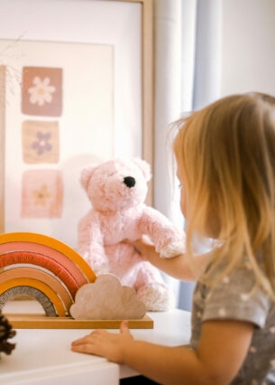 Ein kleines Kind mit einem Teddy und Holzspielzeug