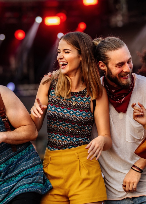 Vier gut gelaunte, junge Menschen auf einem Festival.