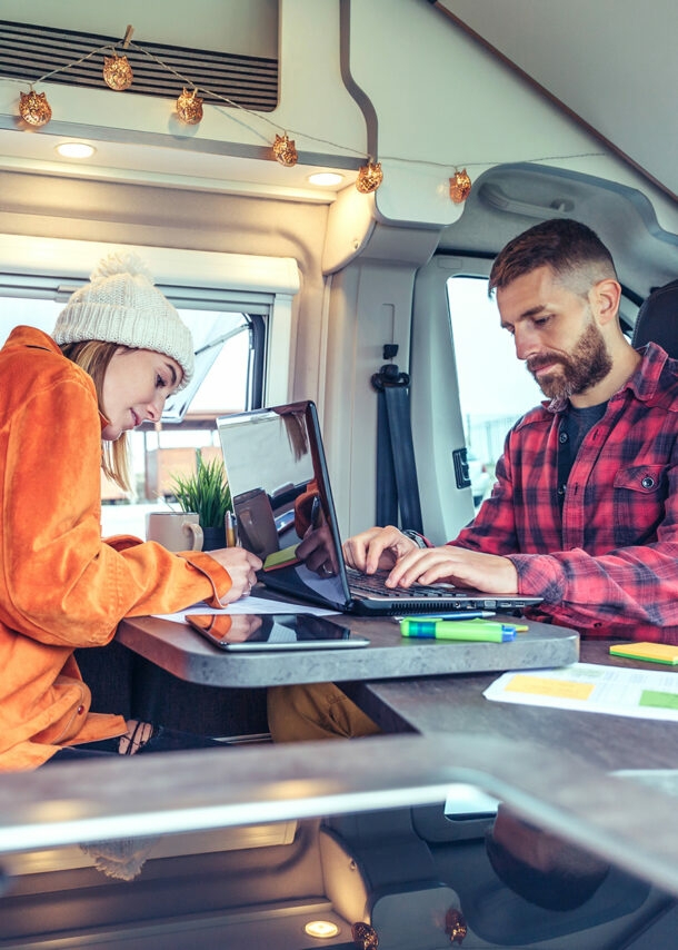 Junges Paar arbeitet am Laptop im Wohnmobil