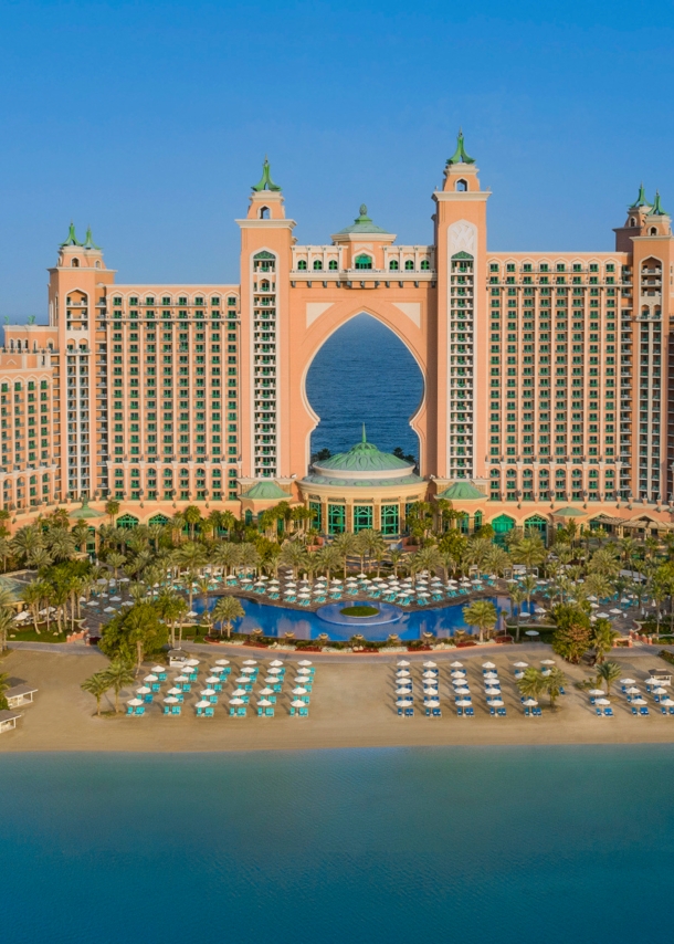 Großer Hotelkomplex im arabischen Stil auf einer Landzunge mit Sandstrand, umgeben von blauem Wasser.