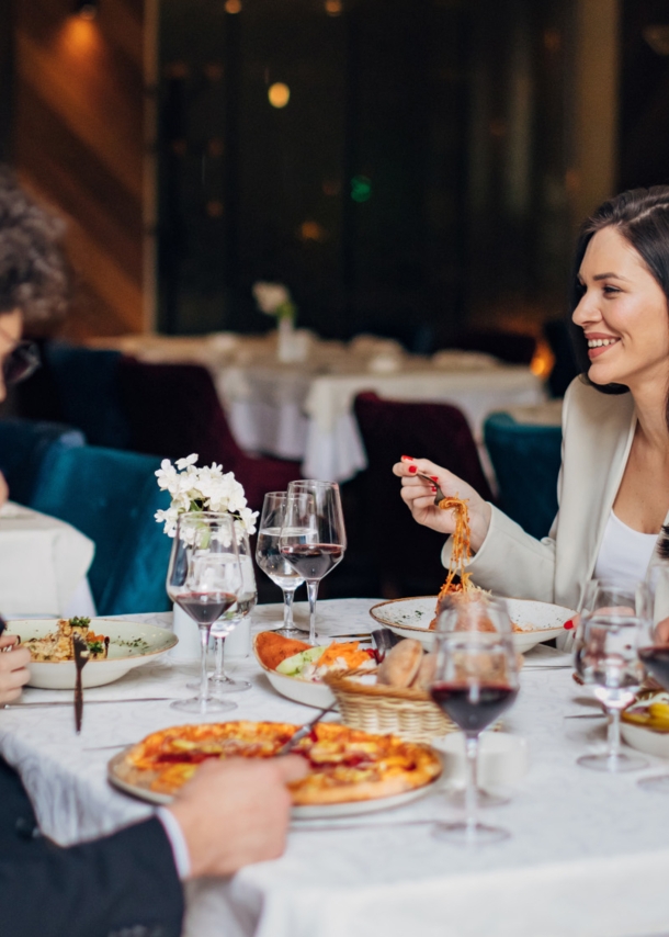 Vier elegant gekleidete Personen sitzen beim Essen an einem Tisch in einem Restaurant.