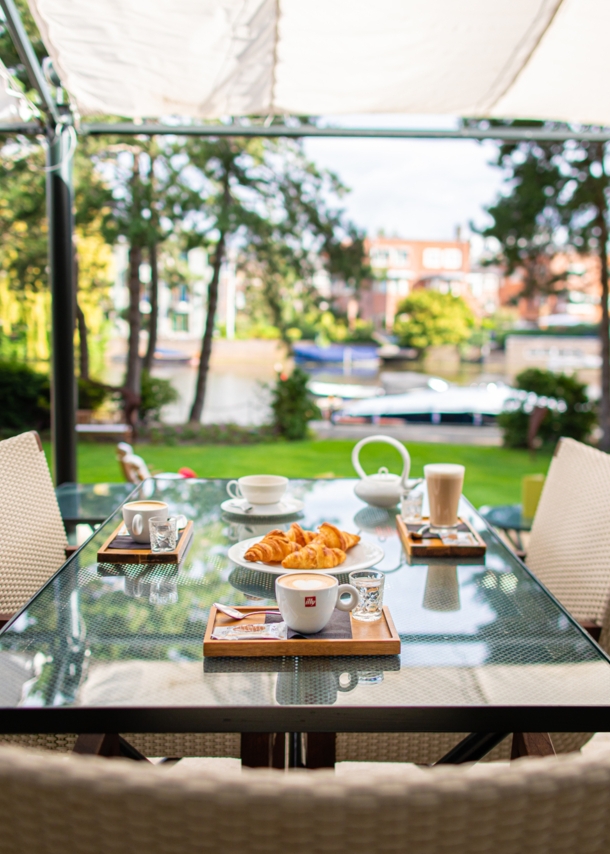 Frühstück auf einem Tisch auf einer Hotelterrasse an einem Kanal.