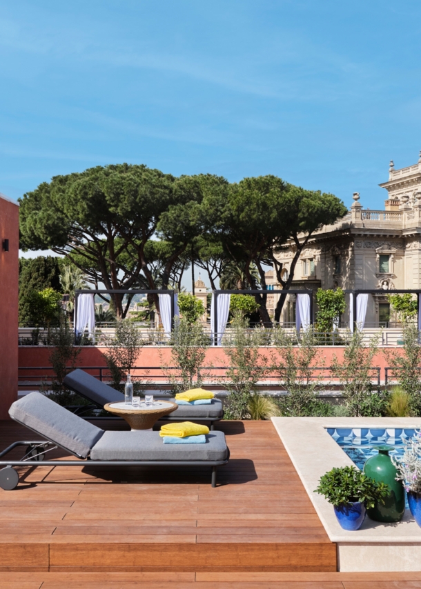 Dachterrasse mit Sonnenliegen an einem Pool im Stadtzentrum Roms.