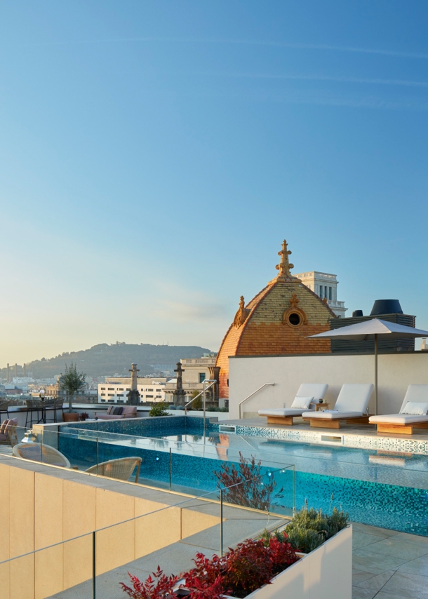 Hotelpool mit Sonnenliegen auf einer modernen Dachterrasse im Stadtzentrum.