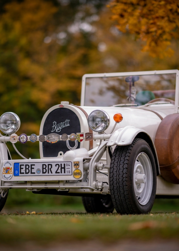 Weißer Bugatti Cabriolet Oldtimer mit H-Kennzeichen in einem Park.