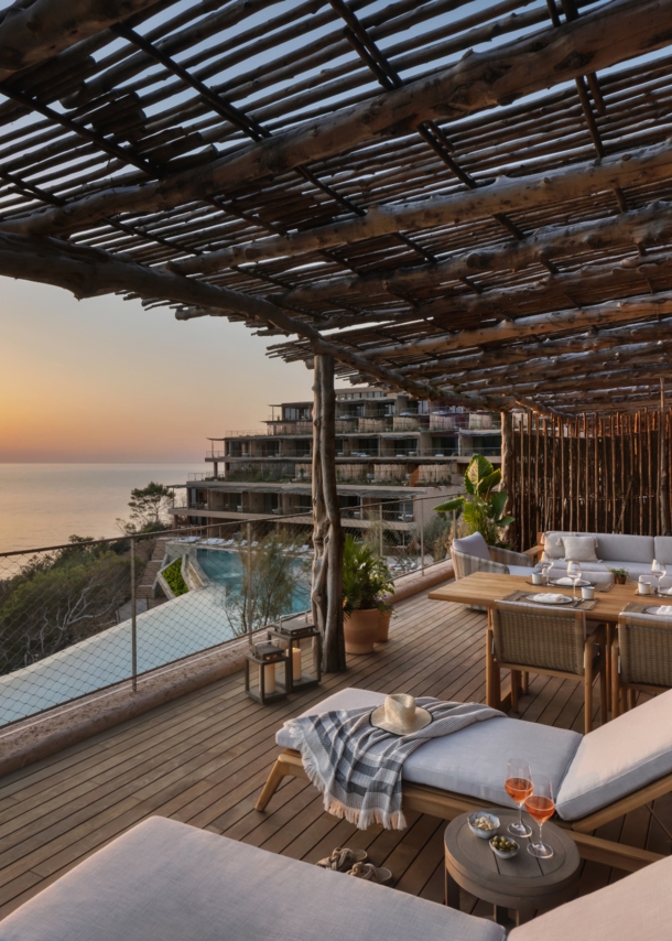 Luxuriöse Hotelterrasse mit Holzpergola am Meer bei Sonnenuntergang.