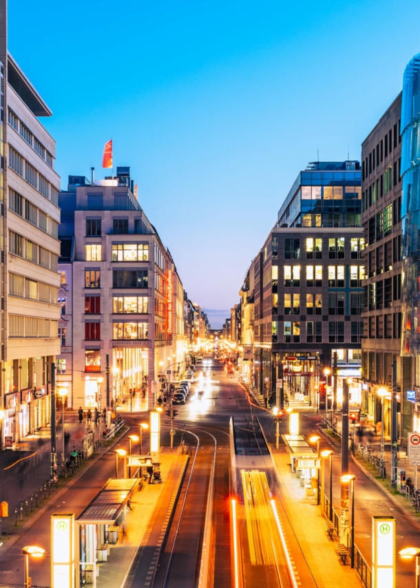 Einkaufsstraße im Stadtzentrum mit beleuchteten Gebäuden bei Abenddämmerung.