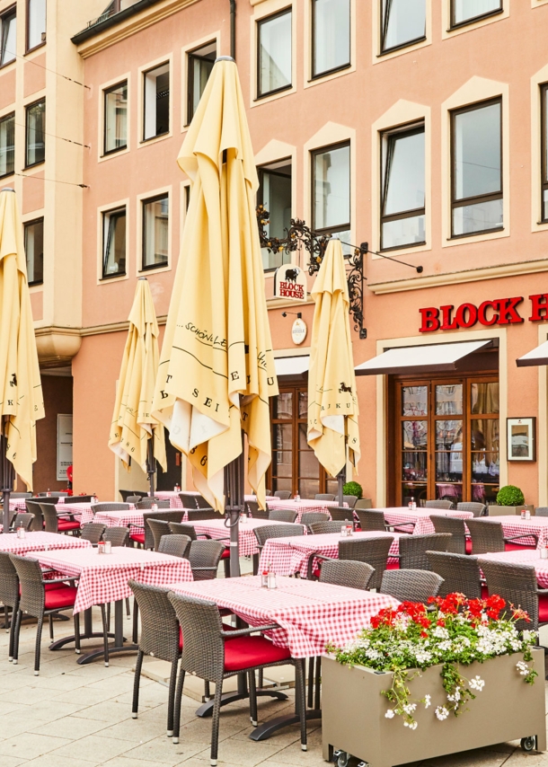 Block House Restaurant mit Außengastronomie auf einem Platz in einer Altstadt.