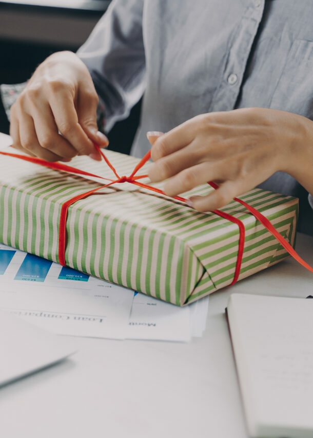 Frau am Arbeitsplatz verpackt ein Geschenk