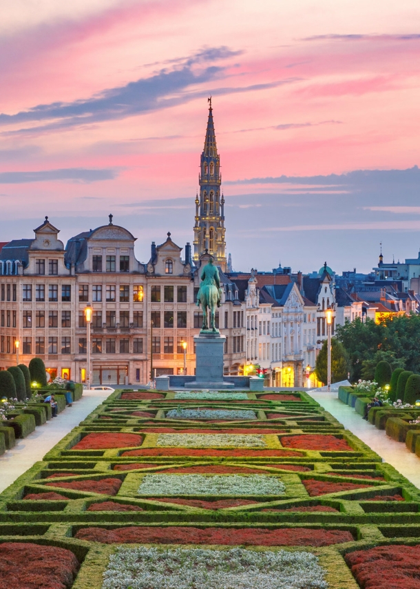 Skyline von Brüssel mit Parkanlage im Vordergrund bei Abenddämmerung unter rosagefärbtem Himmel.