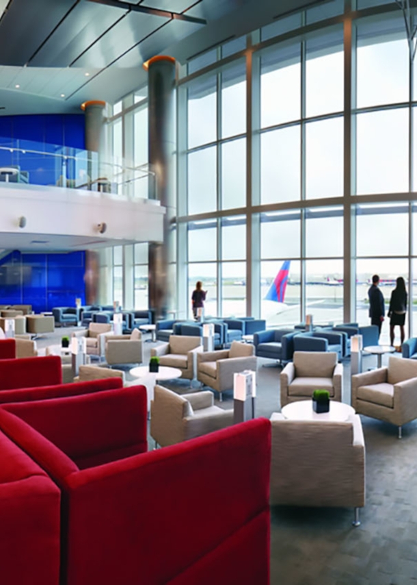 Geräumige Flughafen-Lounge in den Farben Rot, Weiß und Blau mit Blick aufs Rollfeld durch Panoramafenster.