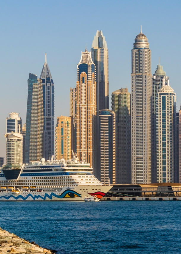 Ein AIDA Kreuzfahrtschiff vor der Skyline Dubais.