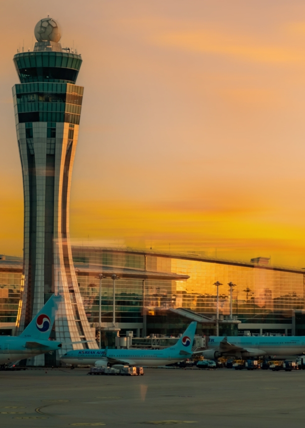 lughafenterminal mit Tower und geparkten Flugzeugen bei Sonnenuntergang.