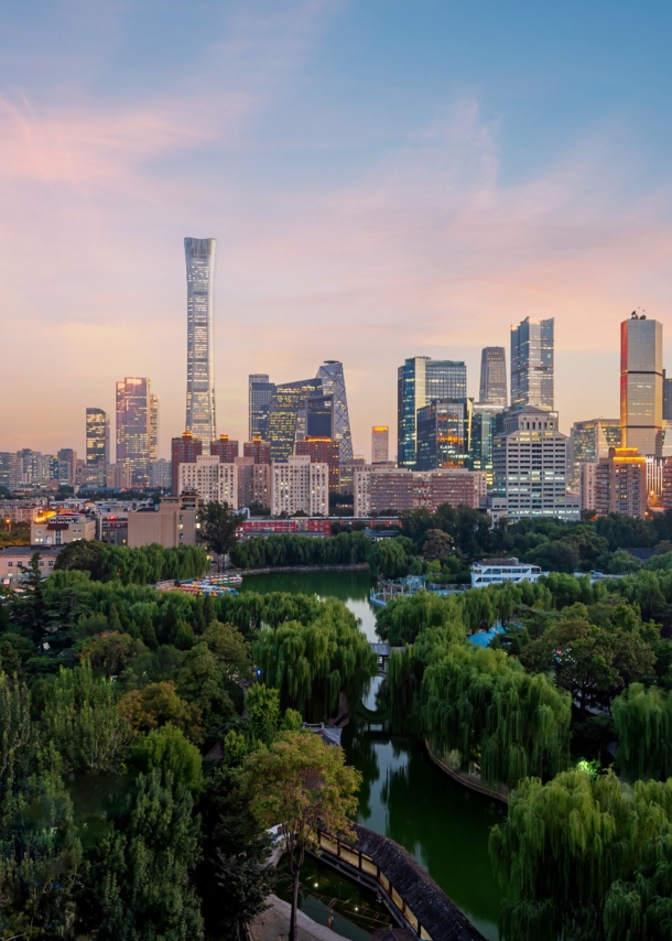 Erleuchtete Skyline von Peking mit Parkanlage in der Dämmerung.