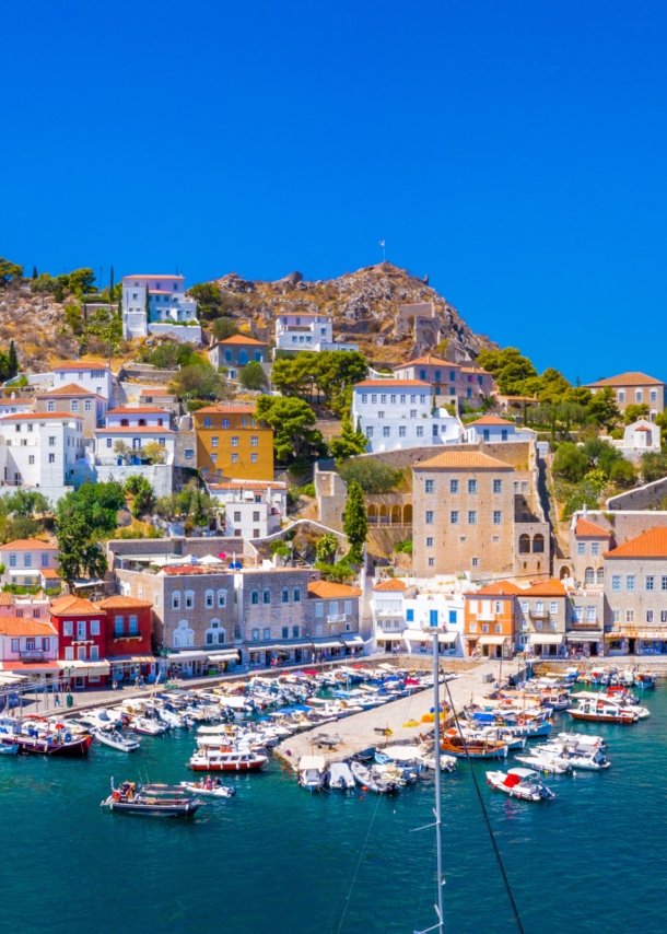 Mediterrane Ortschaft in Hanglage am Meer mit Hafenpromenade und Fischerbooten.