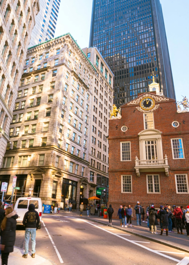 Belebtes Stadtzentrum von Boston mit Hochhäusern und einem kleinen historischen Backsteinhaus.