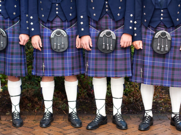 Unterkörper von stehenden Menschen in blauen Kilts