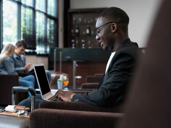 Geschäftsmann arbeitet in Hotellobby am Laptop