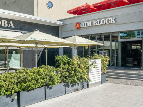 Eingang zu einem Jim Block Restaurant in einem grauen Gebäude.